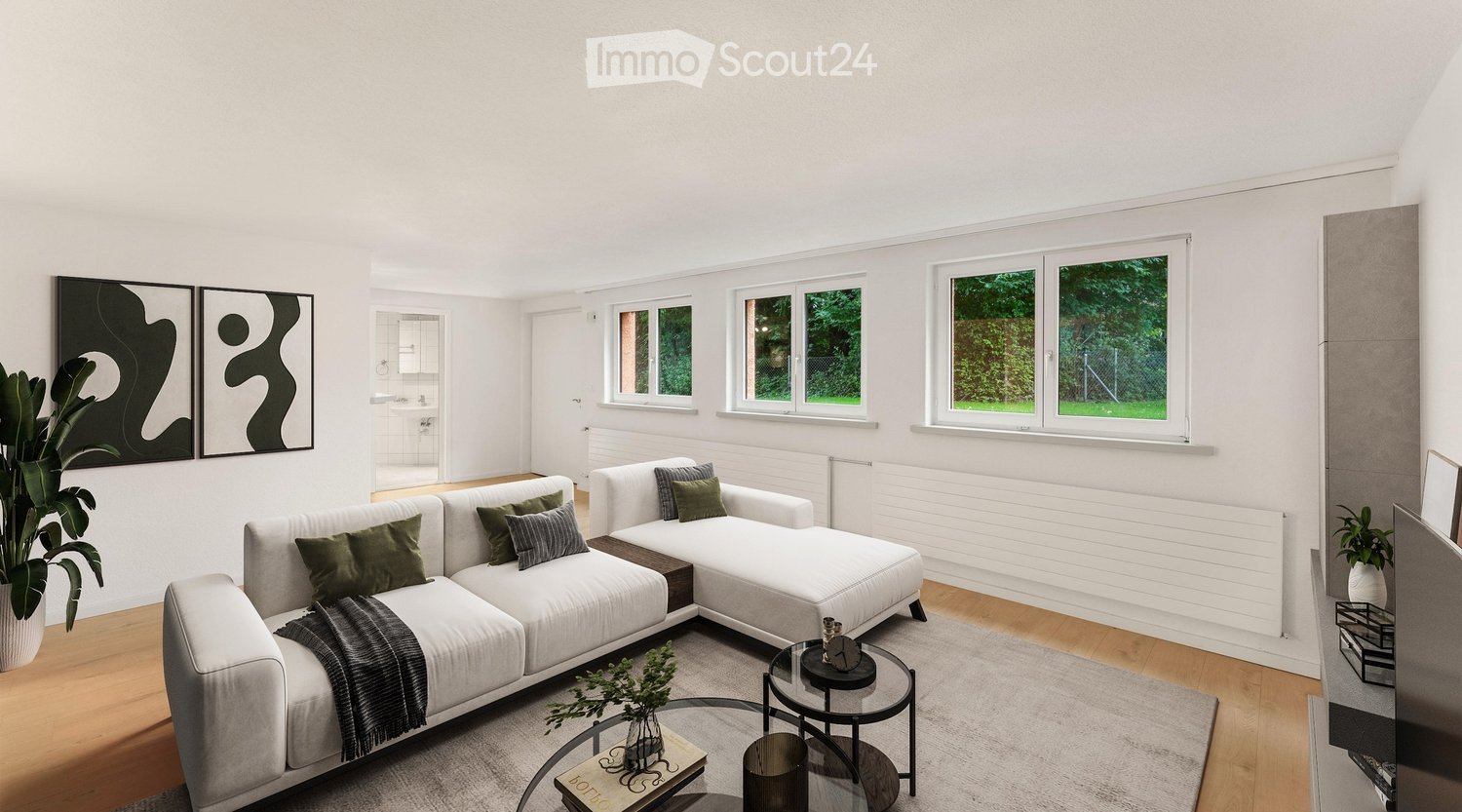 Modern living room with white walls, large windows, grey sectional sofa, coffee table, and decorative plants.