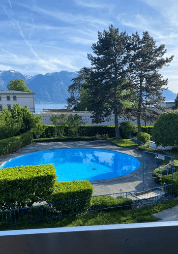 Outdoor swimming pool, fenced garden, hedges, trees, mountains in the background