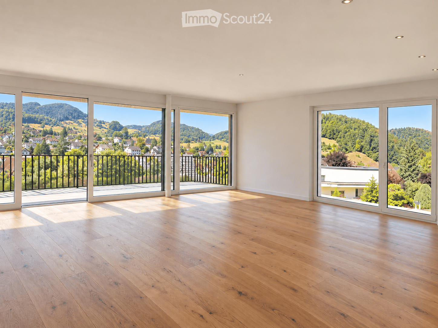 Bright, empty room with large sliding glass doors leading to a balcony, wooden floor, and scenic mountain view.
