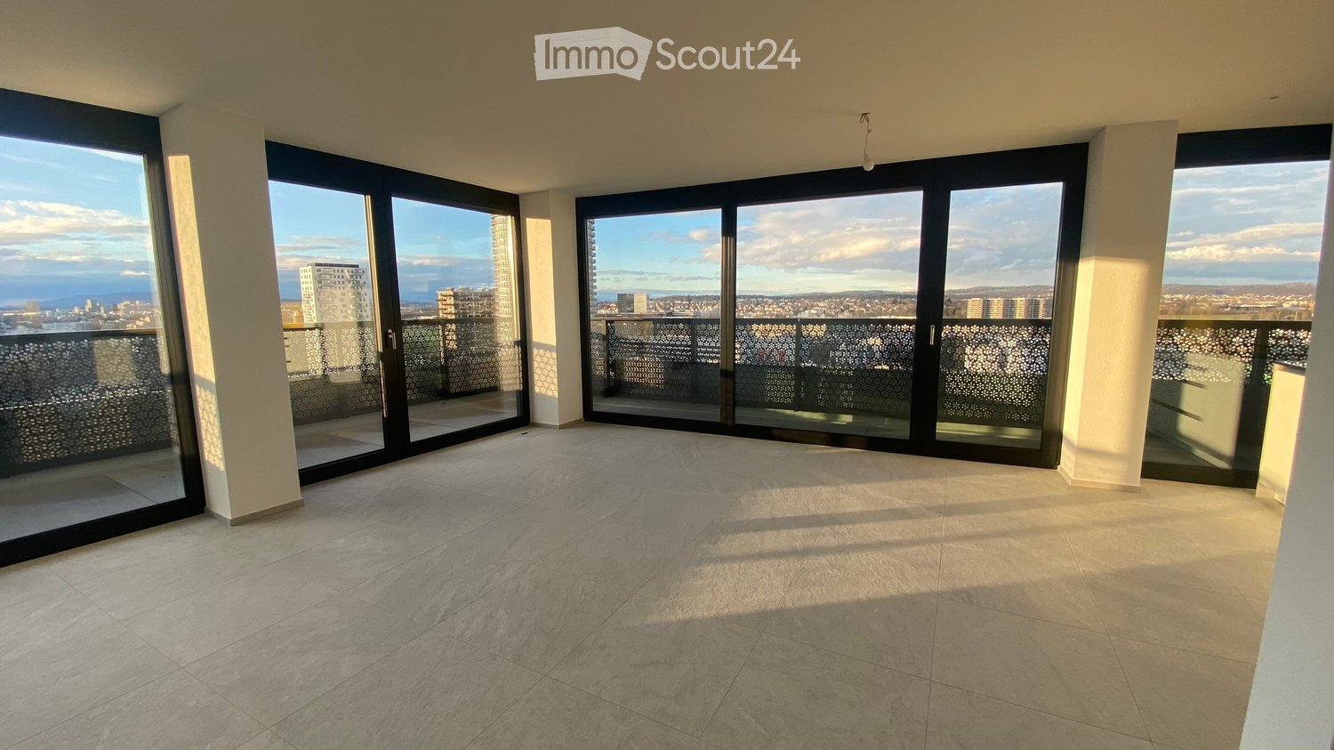 Empty room with large sliding glass doors leading to a balcony, tiled floor, and a view of the cityscape.