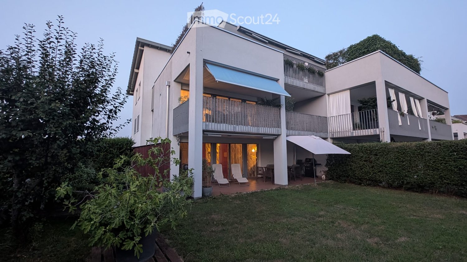 Modern two-story building with balconies, outdoor seating area, and well-maintained garden.