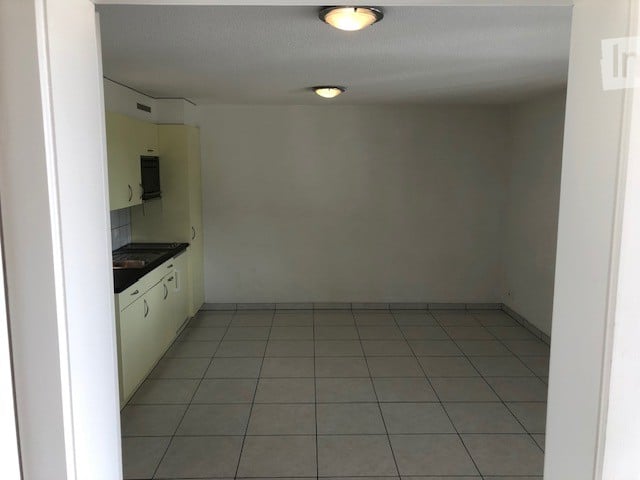 Empty room with tiled floor and light-colored cabinets, no furniture or equipment.
