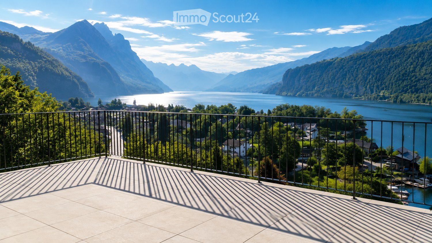 Balcony with a metal railing overlooking a scenic lake and mountain landscape.