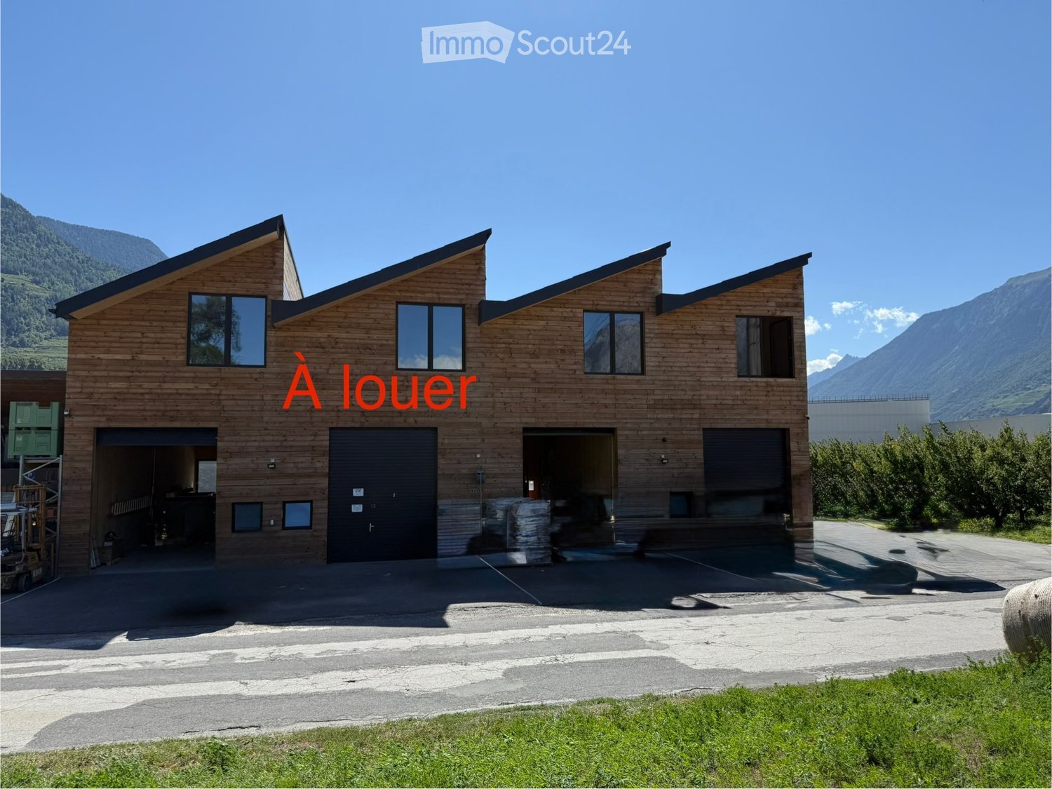modern design, wooden exterior, three garages, two stories, flat roof, several windows, surrounded by mountains