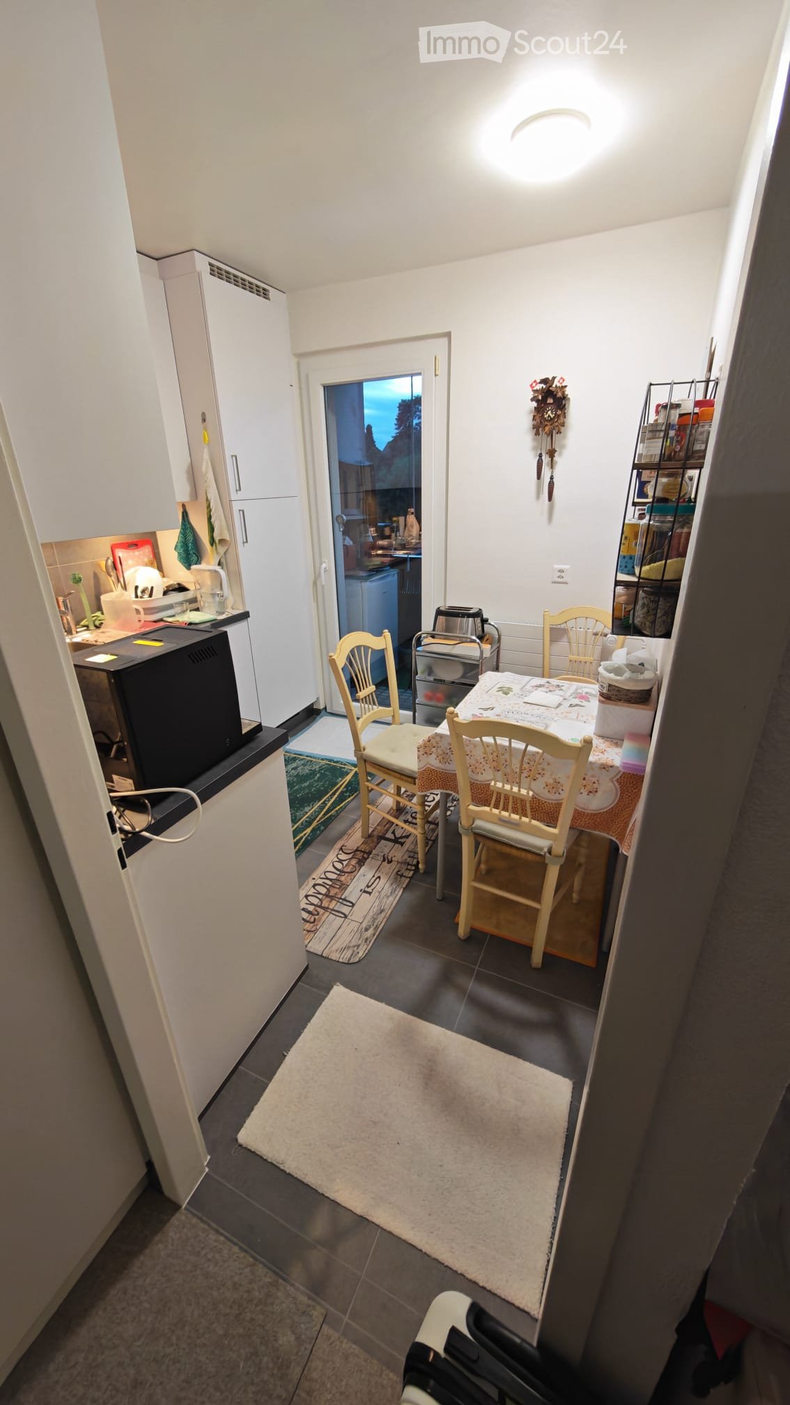 A small, well-lit kitchen and dining area with a dining table, chairs, and various kitchen appliances.