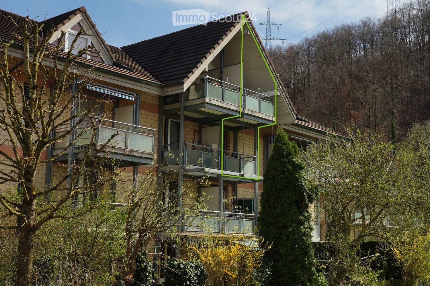 Three-story apartment building, brick exterior, angled roof, balconies on all levels, windows