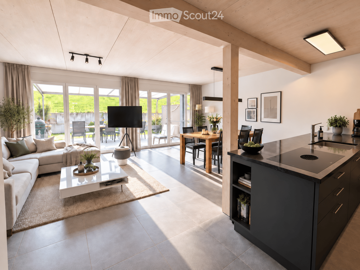 Open-plan living and dining area with a modern sofa, coffee table, dining table, and kitchen island. Large windows and sliding doors lead to an outdoor patio.