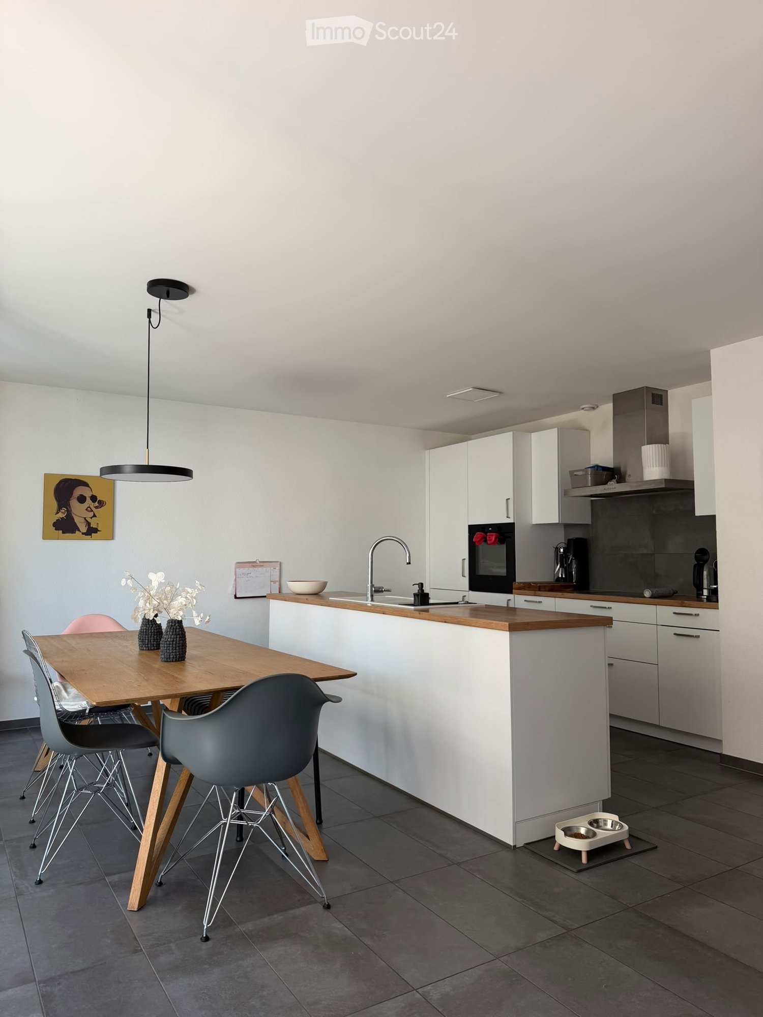 Modern kitchen with white cabinets, wooden countertops, a dining table with chairs, and various appliances including an oven and a faucet.