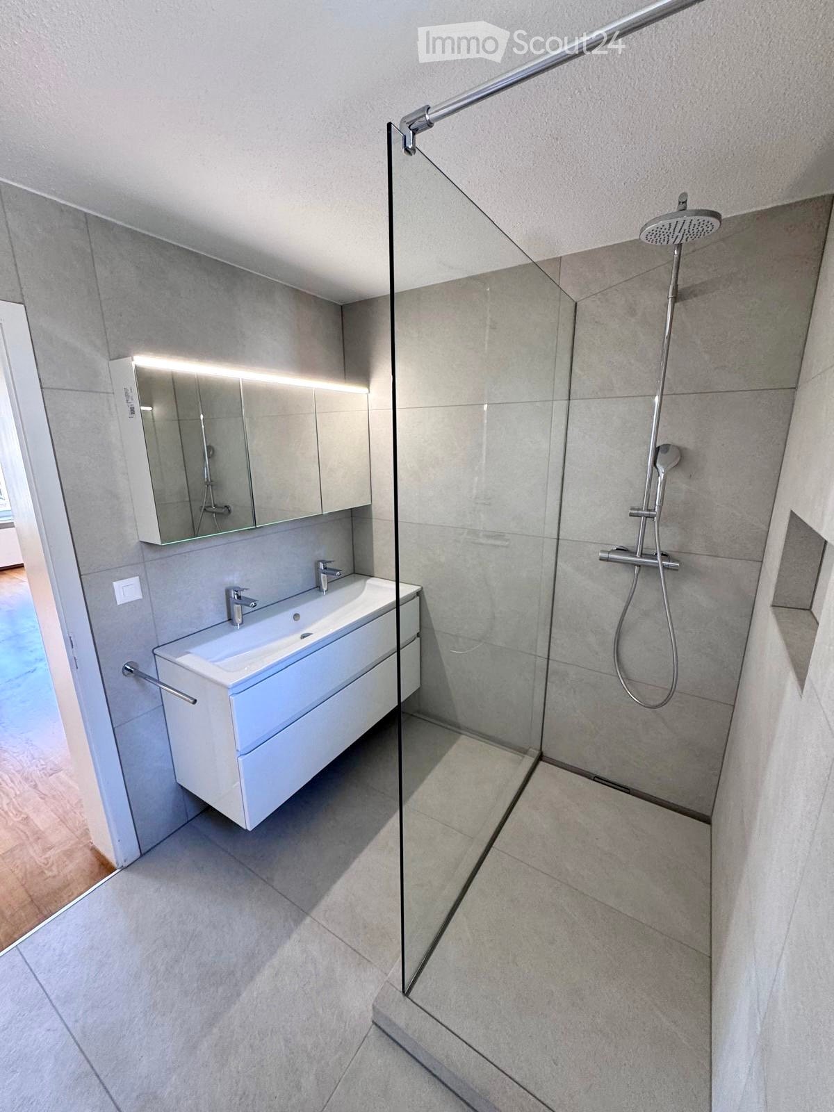 Modern bathroom with a white sink, mirror, and glass-enclosed shower area.