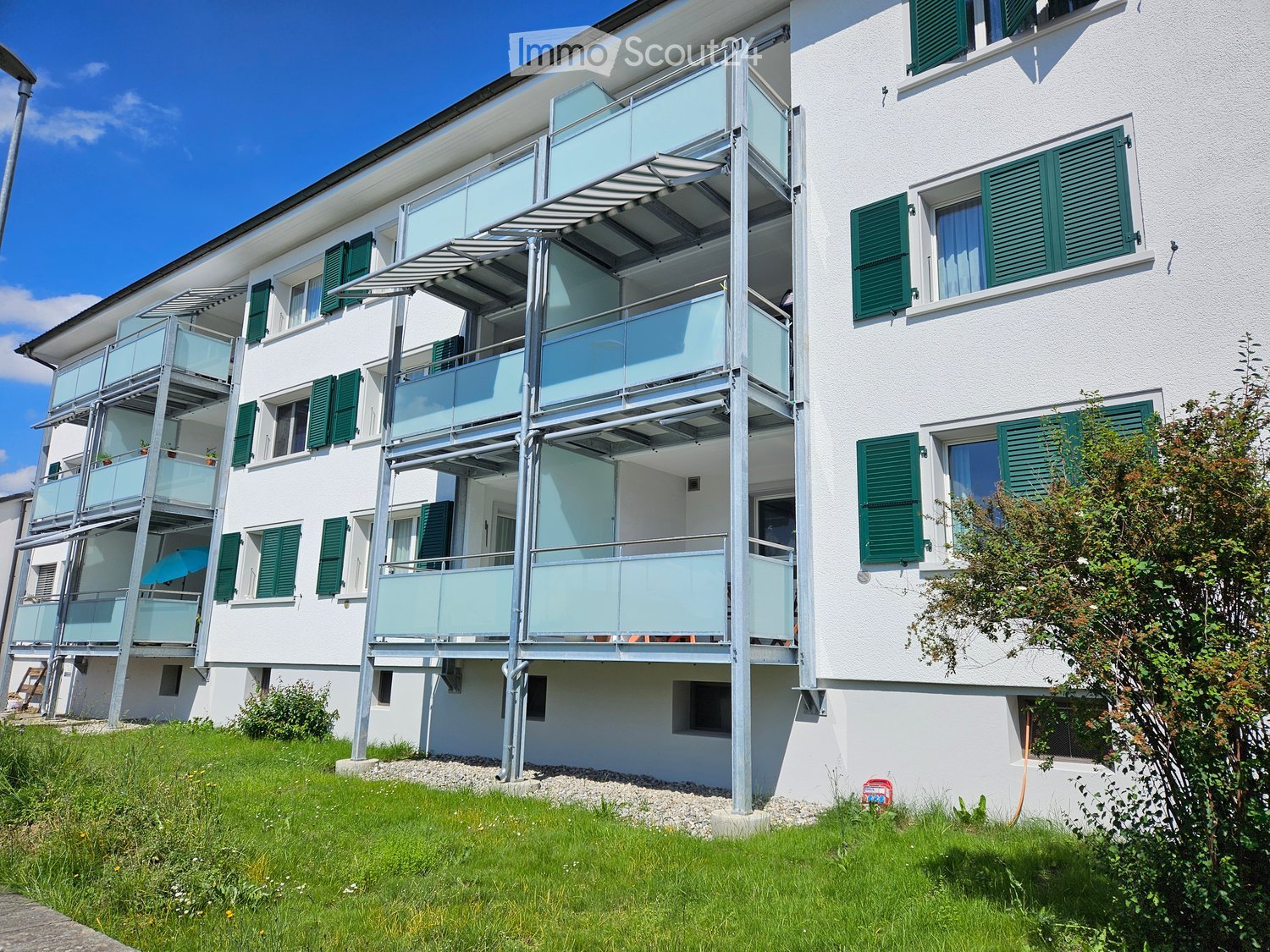 multi-story building with balconies and windows, white exterior, green shutters, modern architecture
