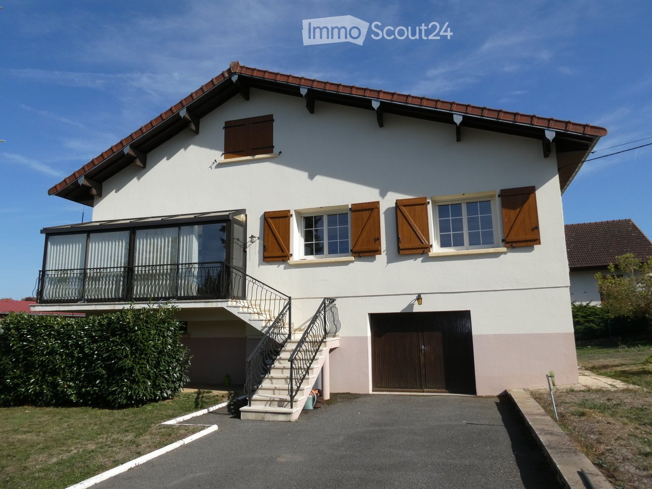Two-story house with white exterior, wooden shutters, garage, and balcony accessible via stairs.