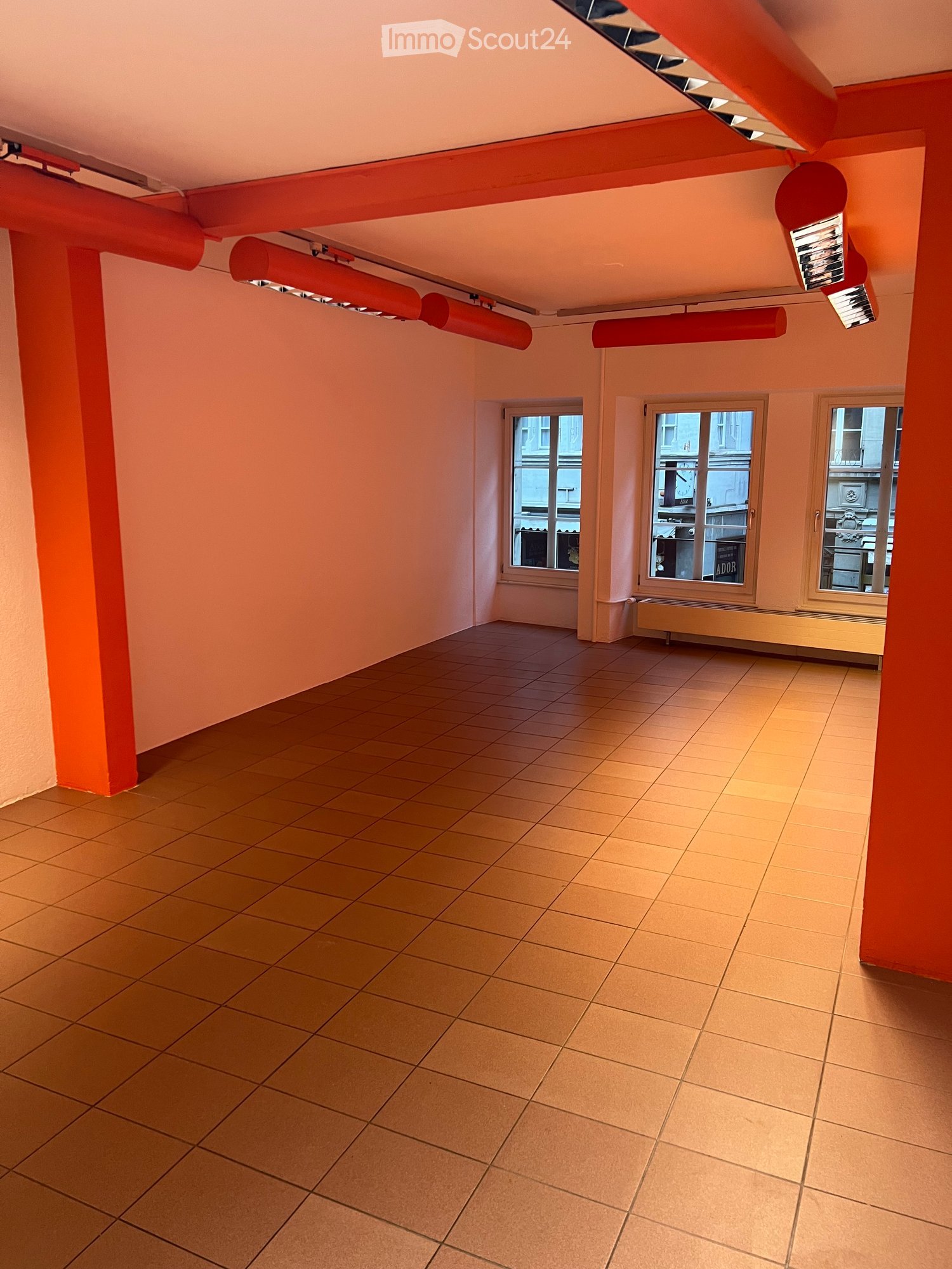 Empty room with tiled floor, light pink walls, and three windows. No furniture or equipment present.