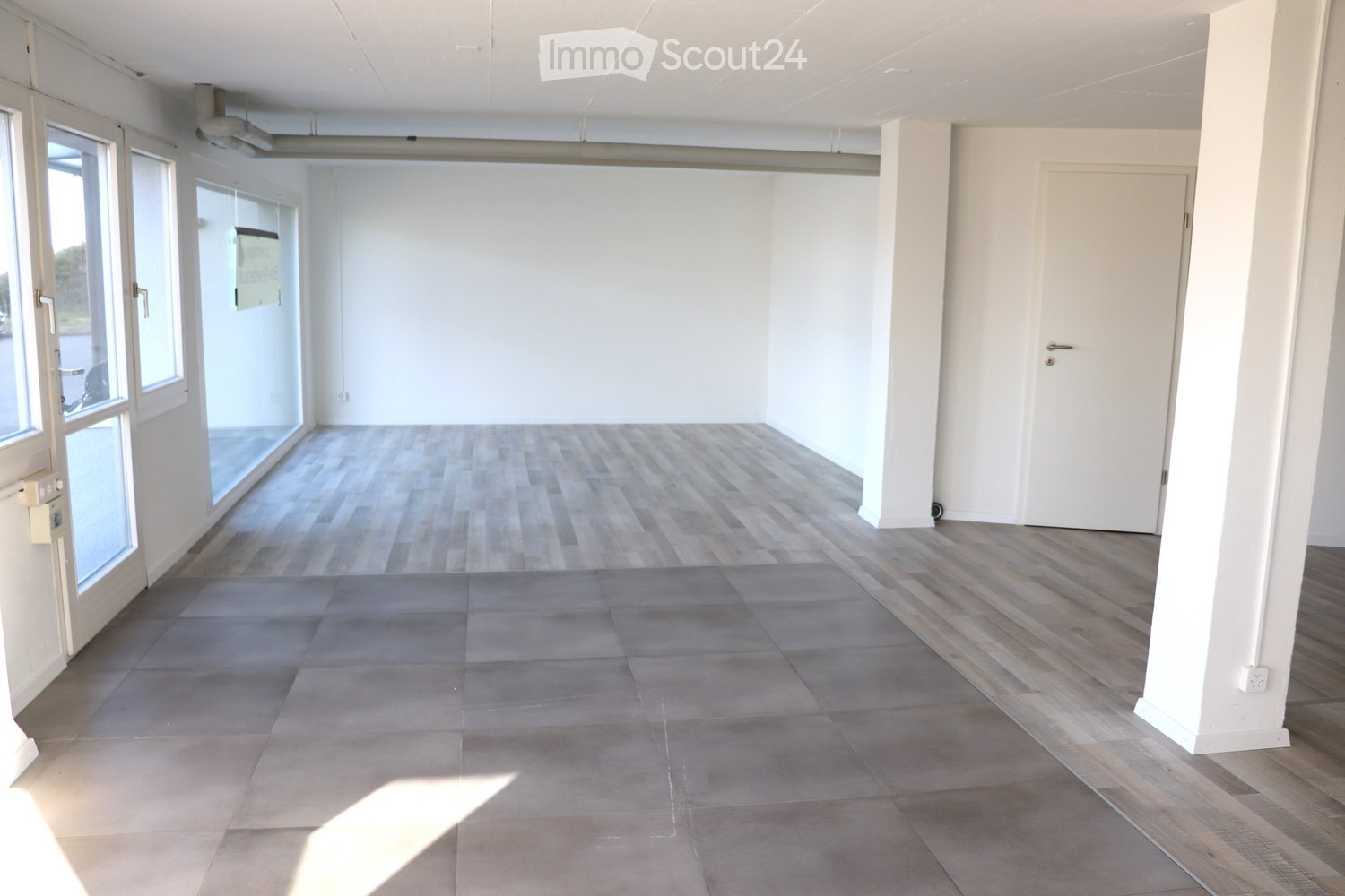 Empty room, gray and white tiled floor, white walls, glass doors, windows