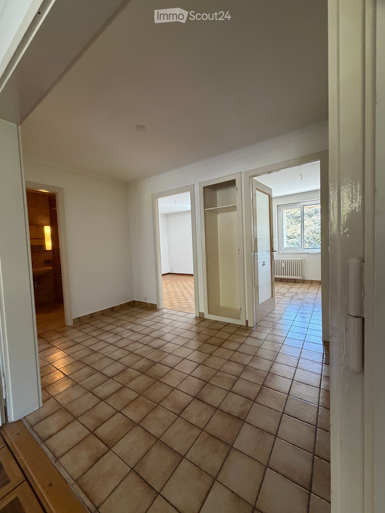 Empty room with tiled floor, white walls, and several open doors leading to other rooms.