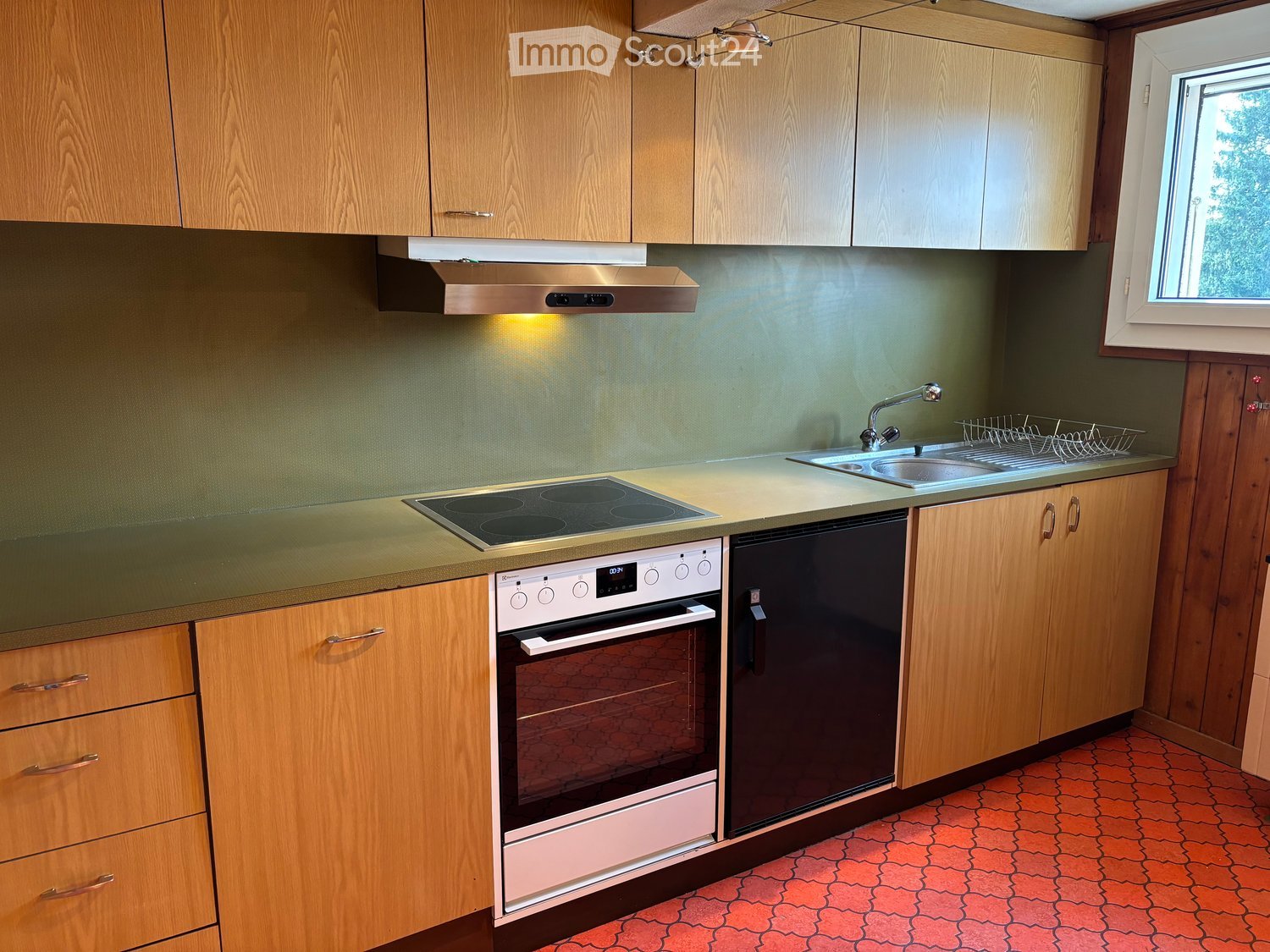 Modern kitchen with wooden cabinets, stainless steel appliances, and a ceramic tile floor.