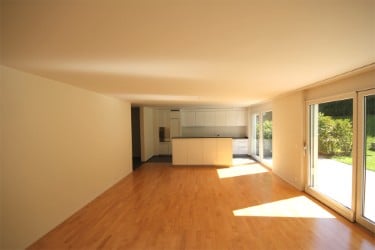 Empty room with wooden flooring, white walls, and large windows. No furniture or equipment present.