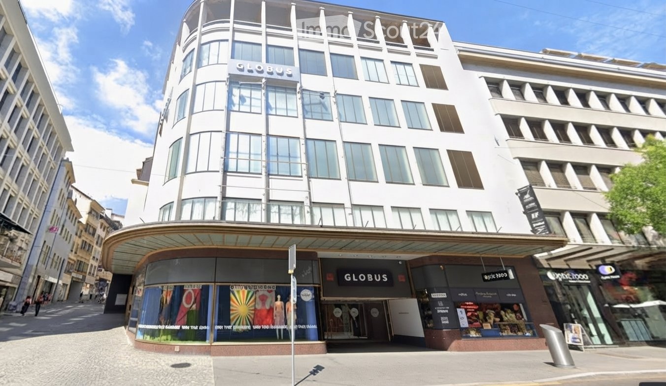 Modern multi-story building with large windows and a curved facade, featuring commercial storefronts at the ground level with signage for 'Globus' and other businesses.