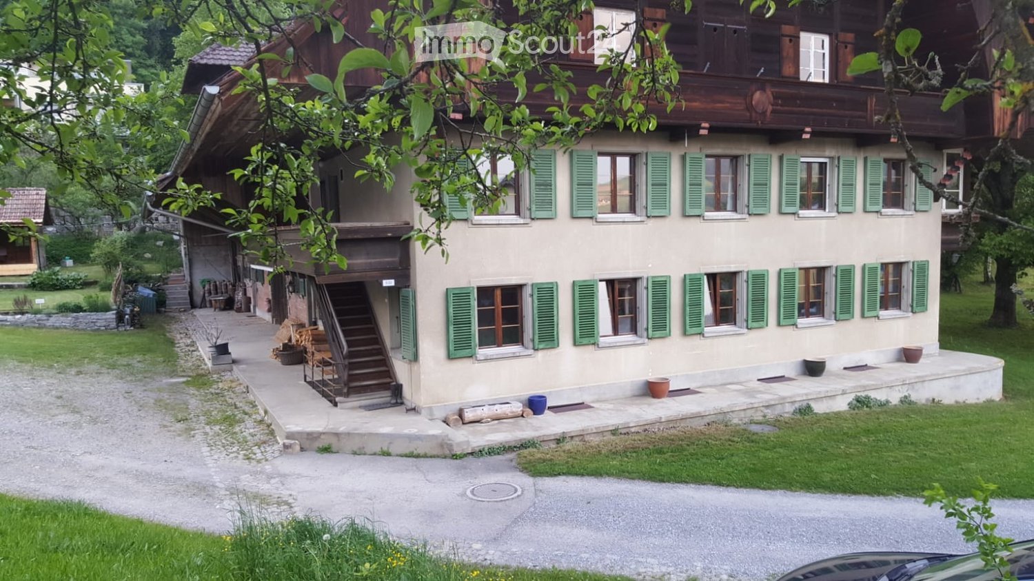 2 story house, brown wood exterior, green shutters, gravel driveway, exterior staircase