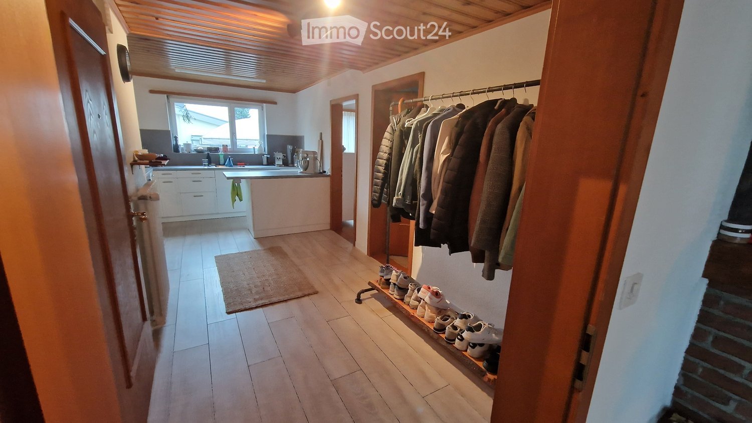 wooden floor, white walls, clothes rack, shoes rack, kitchen with countertop, sink, and window