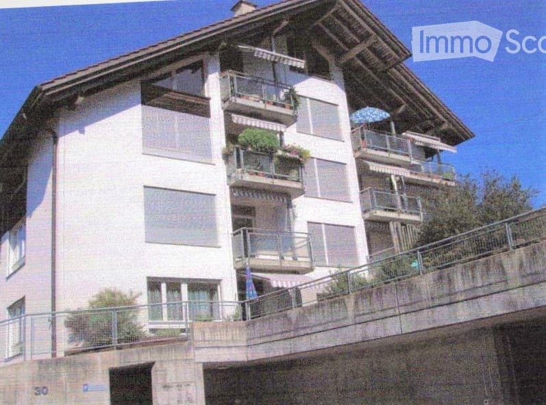 Multi-story residential building with balconies, large windows, and a modern design.