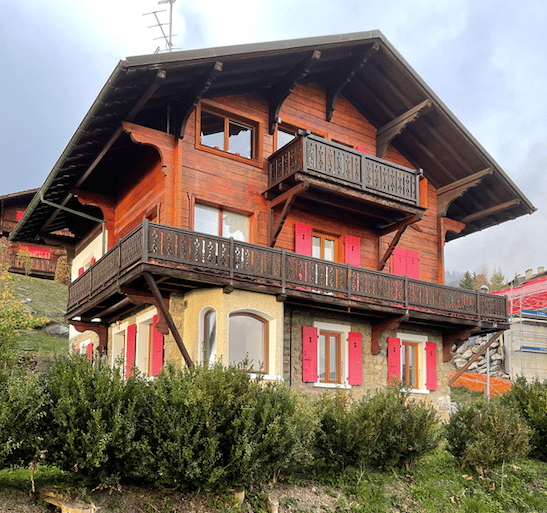 2-story wooden chalet-style house with red exterior, large balconies, and wooden beams