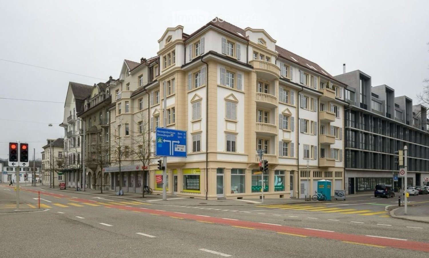 Multi-story building with classic European architecture, featuring ornate facades, large windows, and balconies. The building has a mix of residential and commercial spaces with storefronts on the ground floor.