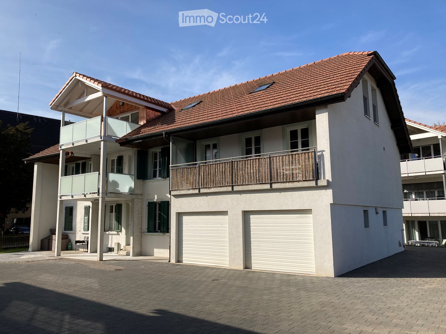 2 story house, white exterior, brown roof, 2 garages, balcony