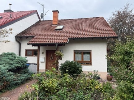 Single-story house with red-tiled roof, white exterior, and small garden area.