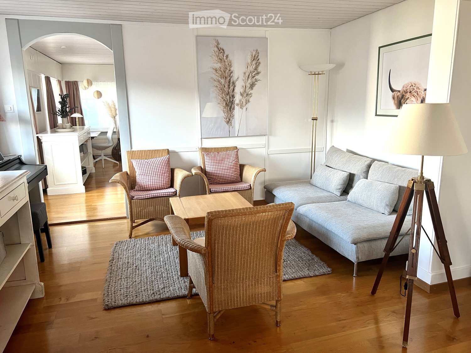 wooden floor, living room furniture, L-shaped sofa, coffee table, armchairs, carpets, floor lamp, picture frames