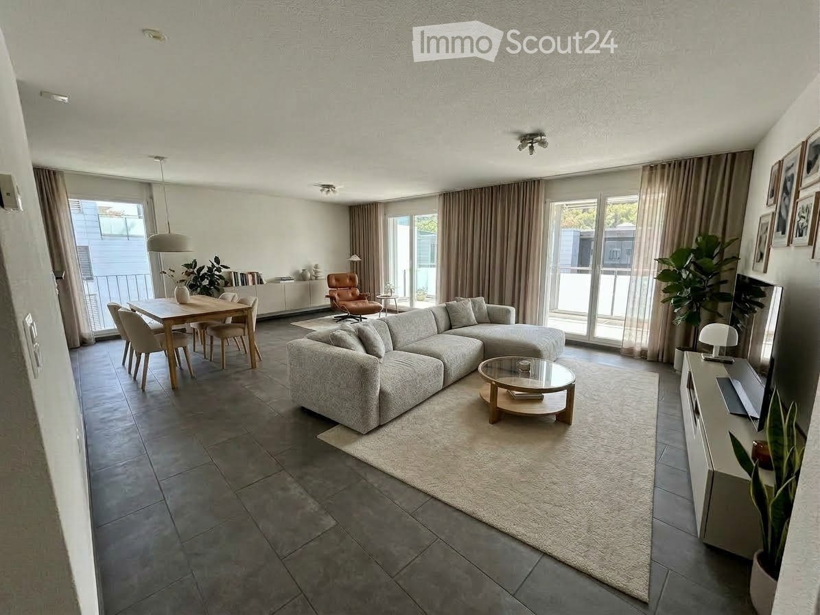 Modern living and dining area with a grey sectional sofa, coffee table, dining table with chairs, TV, and large windows with balcony access.