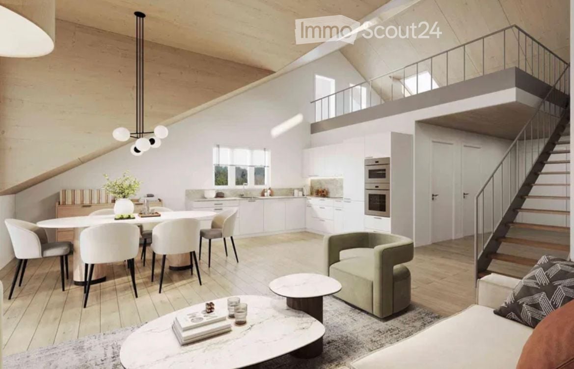 Open-plan living and dining area with modern furniture, including a sofa, coffee table, dining table with chairs, and a staircase leading to an upper level. The kitchen features white cabinets and stainless steel appliances.