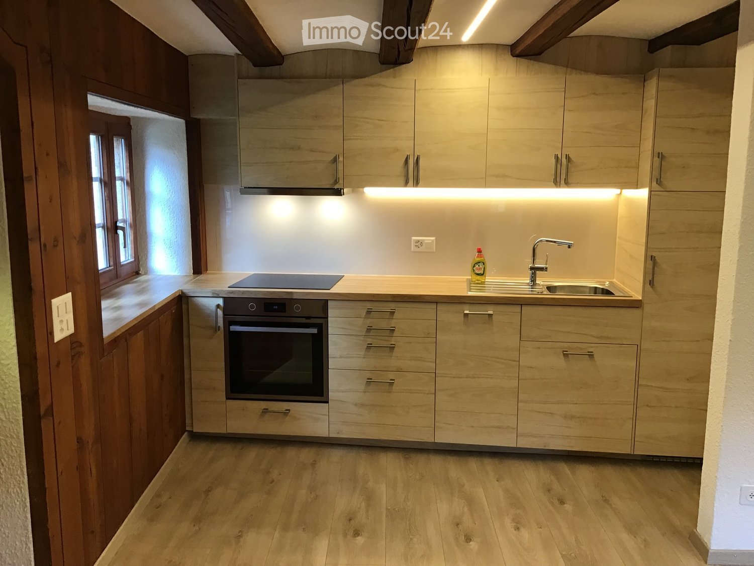 Modern kitchen with light wood cabinets, stainless steel appliances, and a sleek countertop.