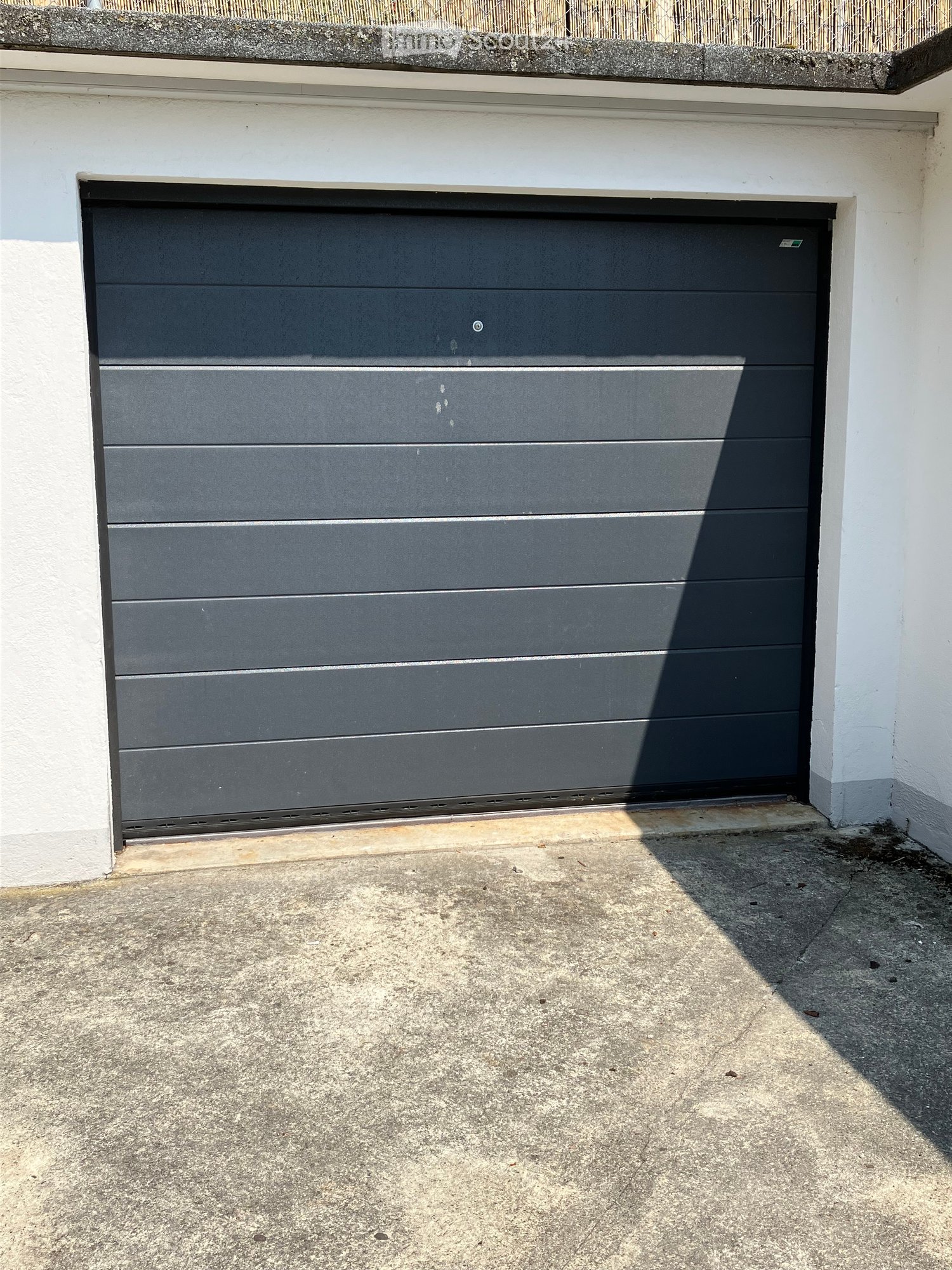 Black steel garage door, gray concrete floor, white wall