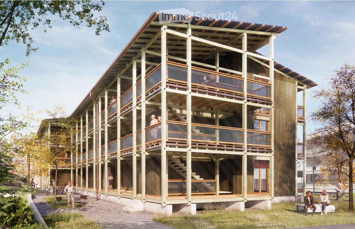 Modern multi-story building with wooden balconies and open walkways, surrounded by greenery and pathways.