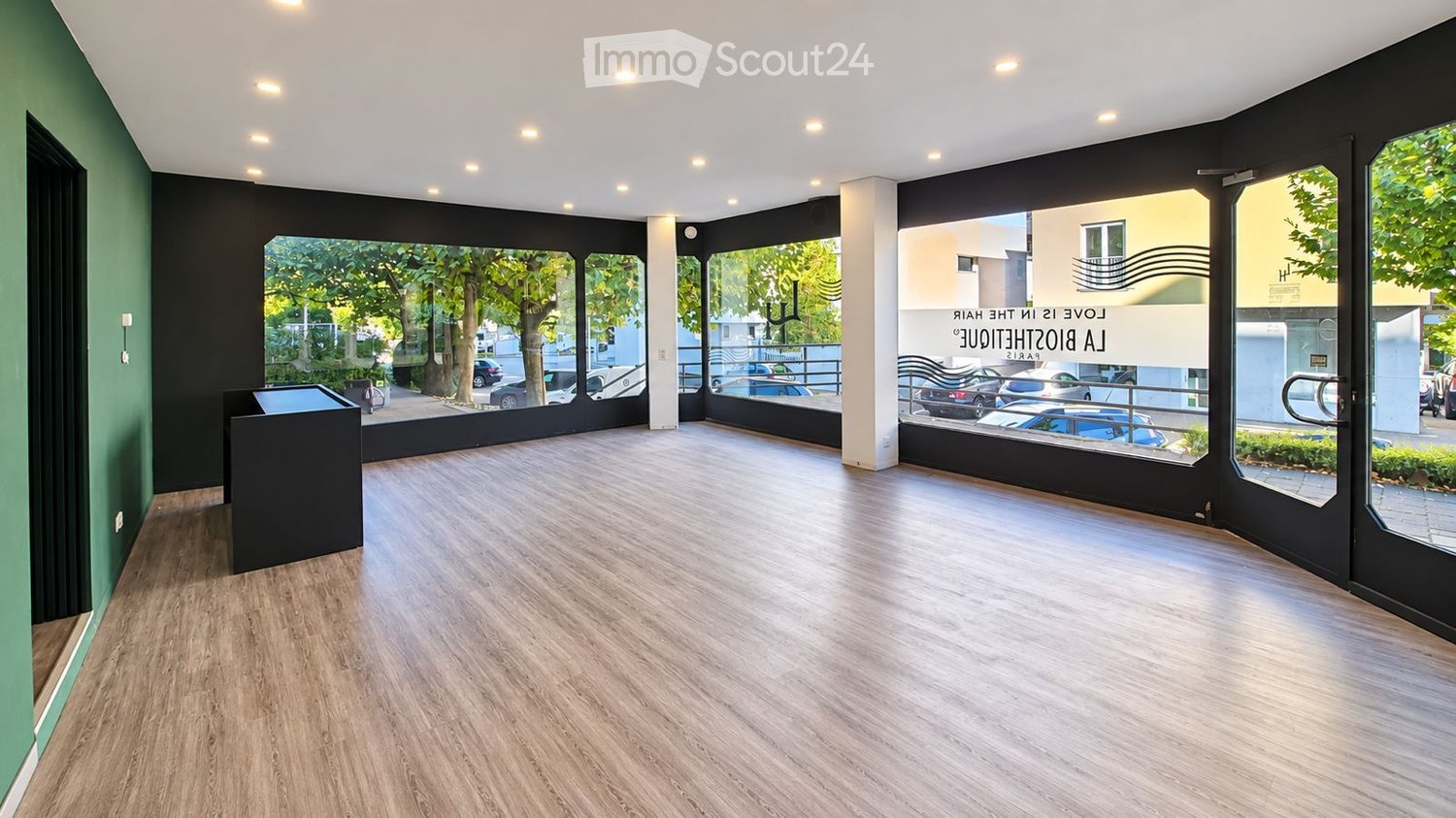 Empty room with wooden flooring, large windows, and modern lighting fixtures. No furniture or equipment present.