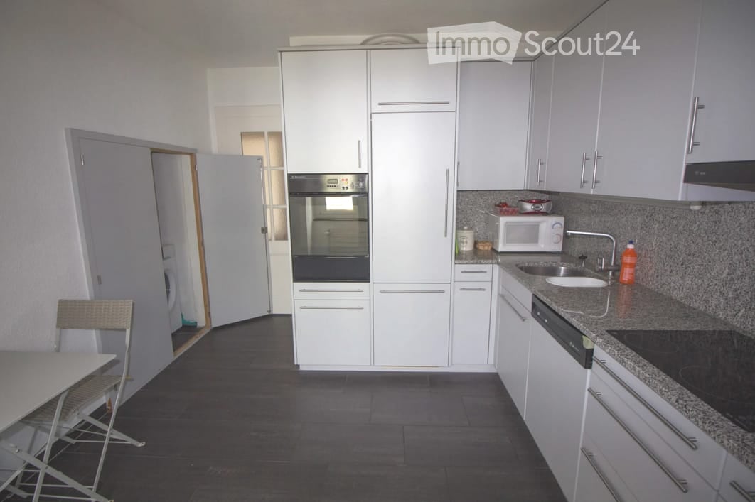Modern kitchen with white cabinets, stainless steel appliances, granite countertop, and a small dining area with a table and chairs.
