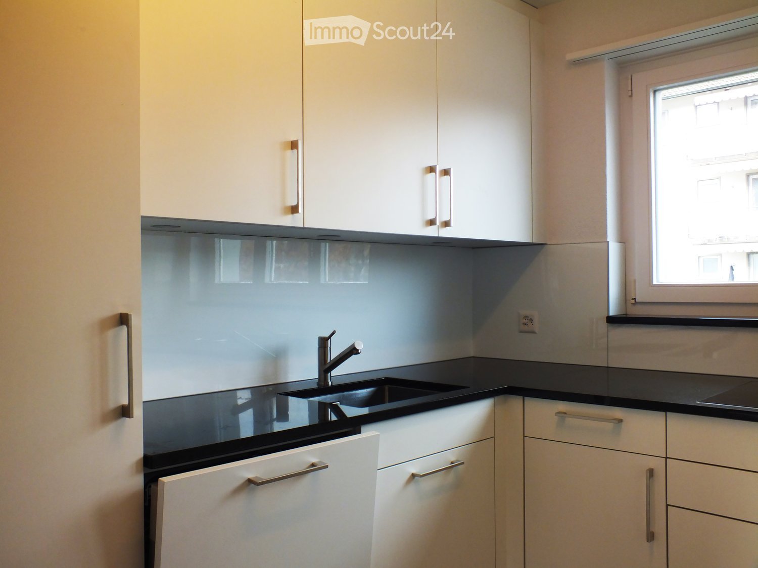 Modern kitchen with white cabinets, black countertops, and a sleek sink with a modern faucet.