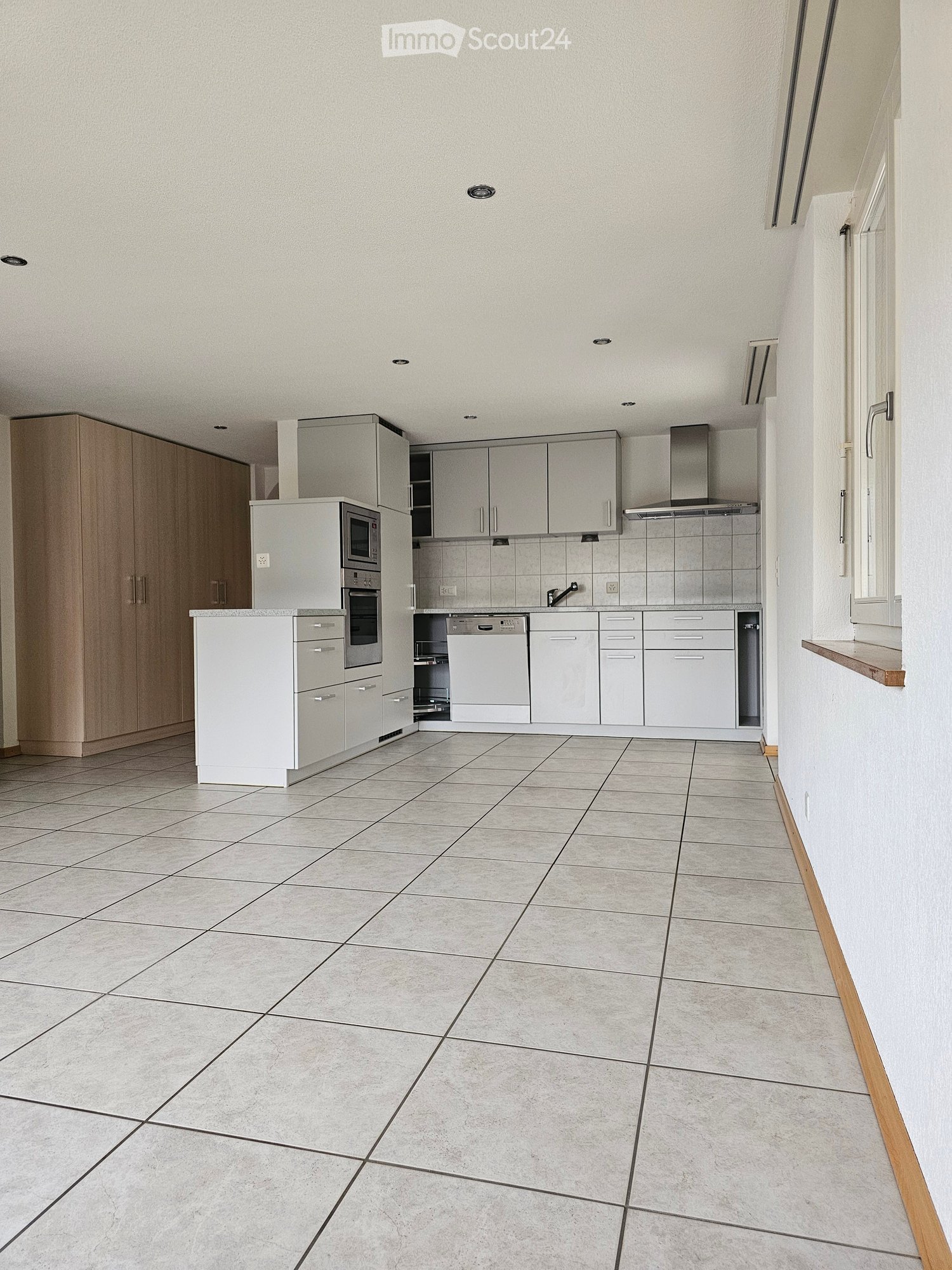 Modern kitchen with white cabinets, tiled floor, microwave, oven, dishwasher, and faucet.