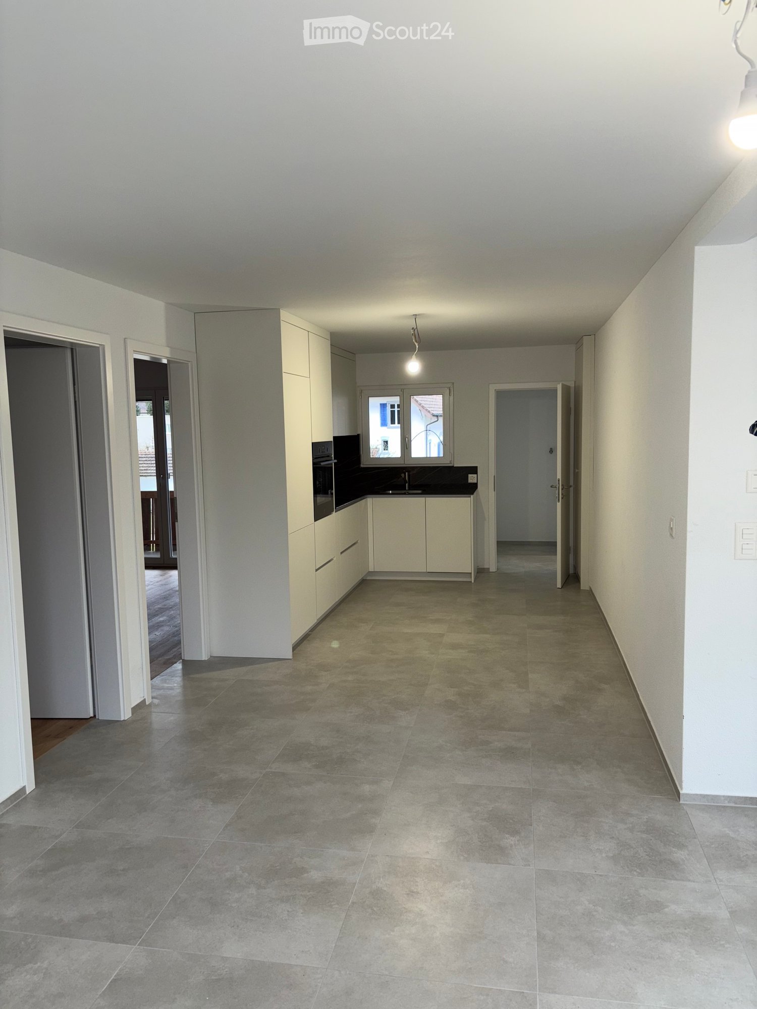 Empty hallway with tiled floor, white walls, and open doorways leading to other rooms.