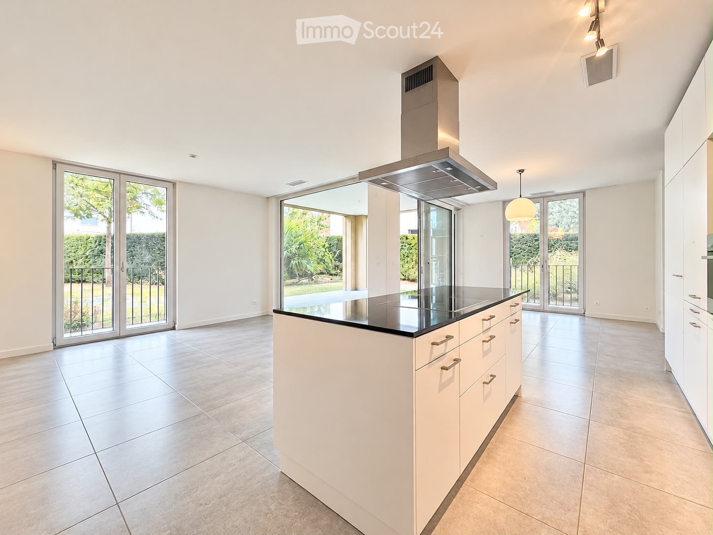 Modern kitchen with white cabinets, a central island, and large glass doors leading to a garden.