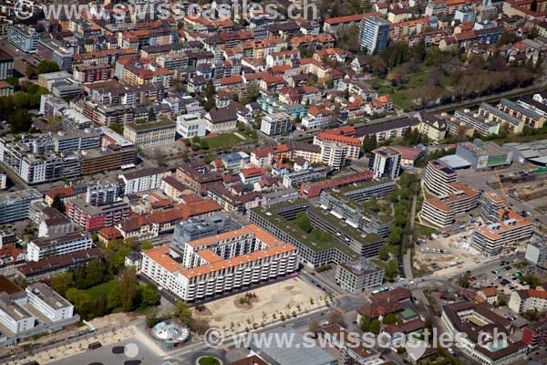 Aerial view of a dense urban area with numerous buildings, roads, and green spaces.