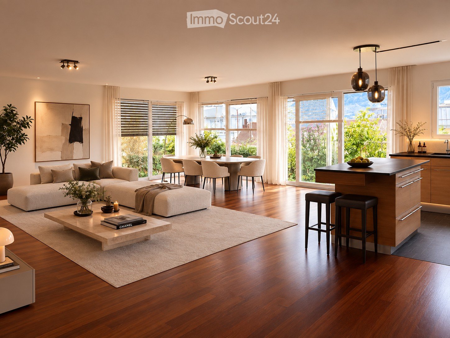 Open-concept living and dining area with a modern sofa, coffee table, dining table, and kitchen island. Large windows provide natural light, and the space is decorated with plants and artwork.