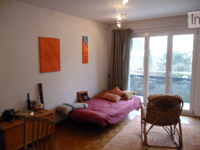 single bed, chair, desk, rocking chair, double doors with balcony access