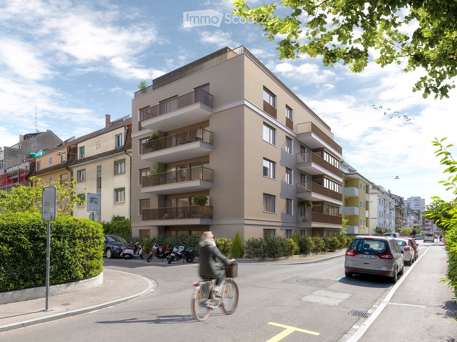 Modern multi-story residential building with balconies, located on a street with parked cars and a cyclist passing by.