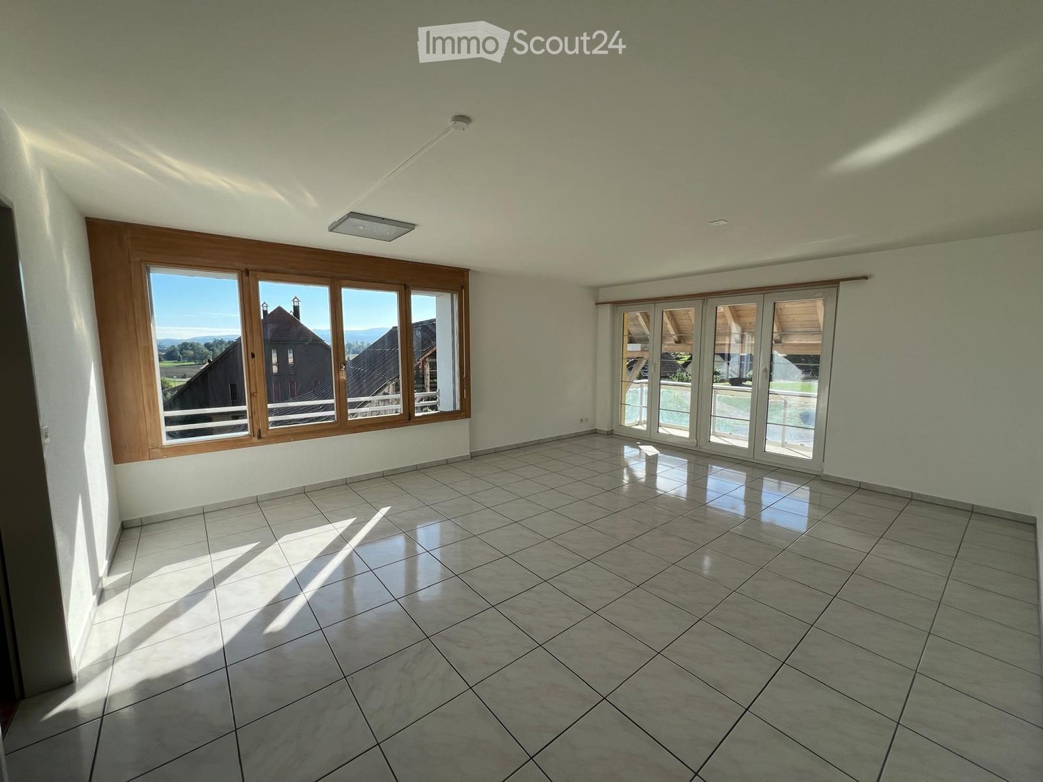 Empty room with tiled floor, large windows, and sliding glass doors leading to an outdoor area.