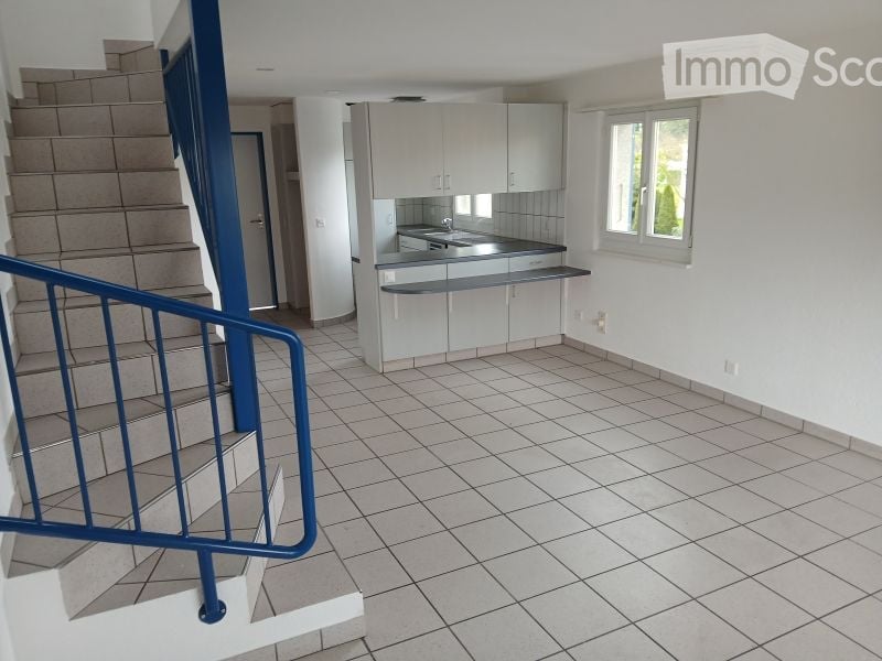 Empty kitchen with white cabinets, tiled floor, and a window. No furniture or appliances are present.
