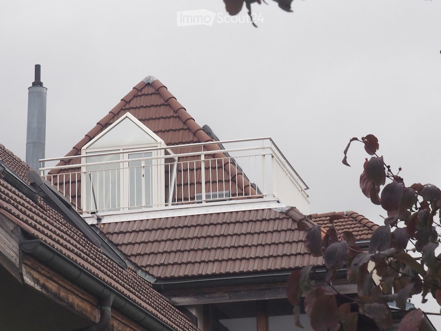 Roof with red tiles, white balcony railing, chimney, and a small dormer window.