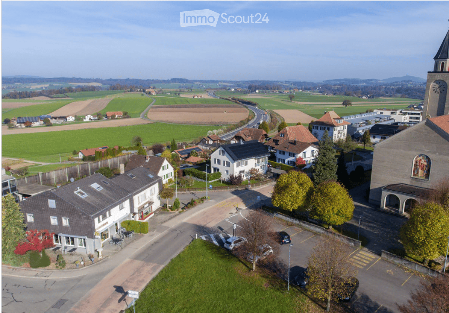 Aerial view of a small town with houses, a church, and surrounding farmland.