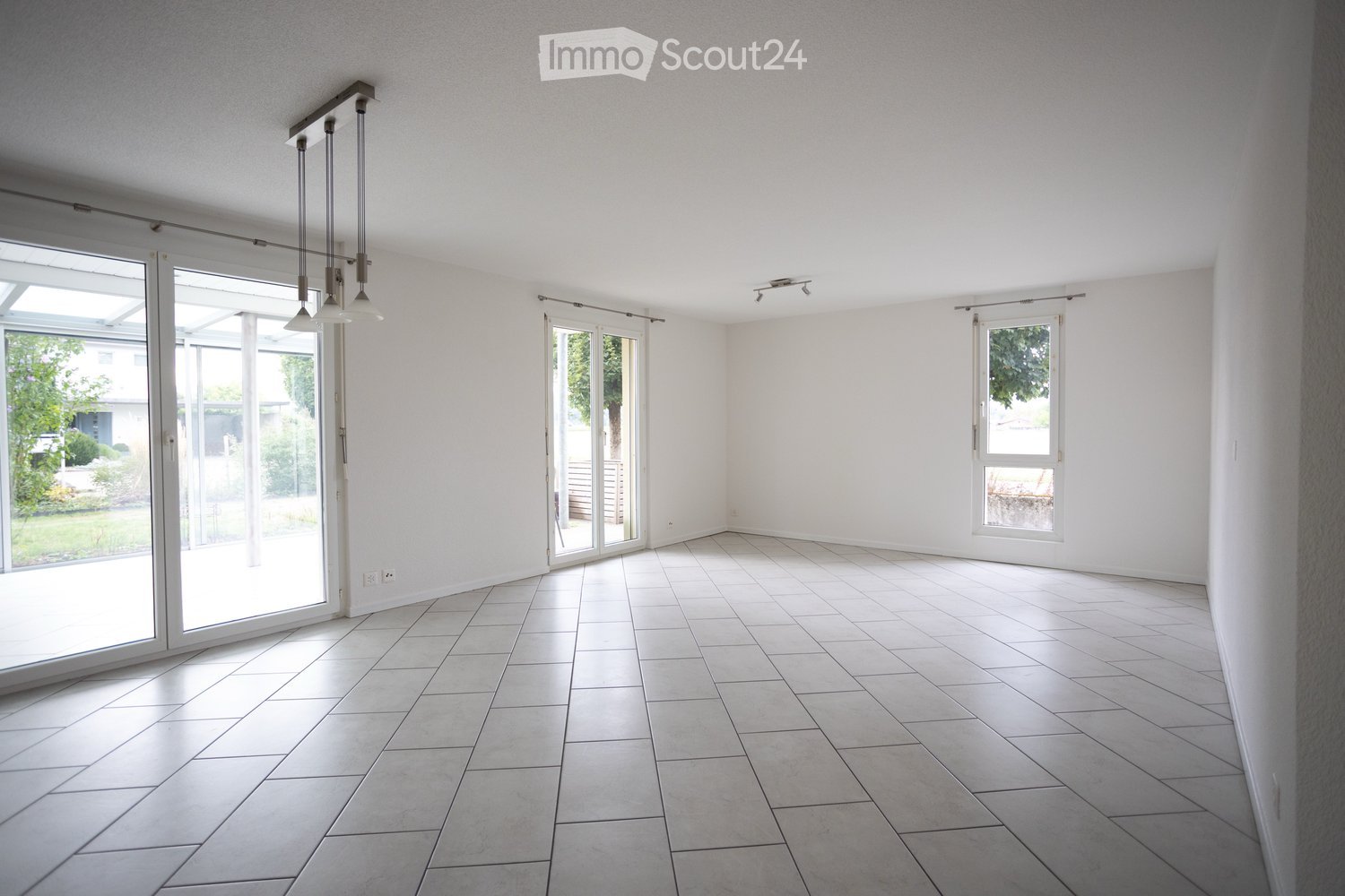 Empty room with white tiled floor, white walls, large sliding glass doors, and a window on the right side.