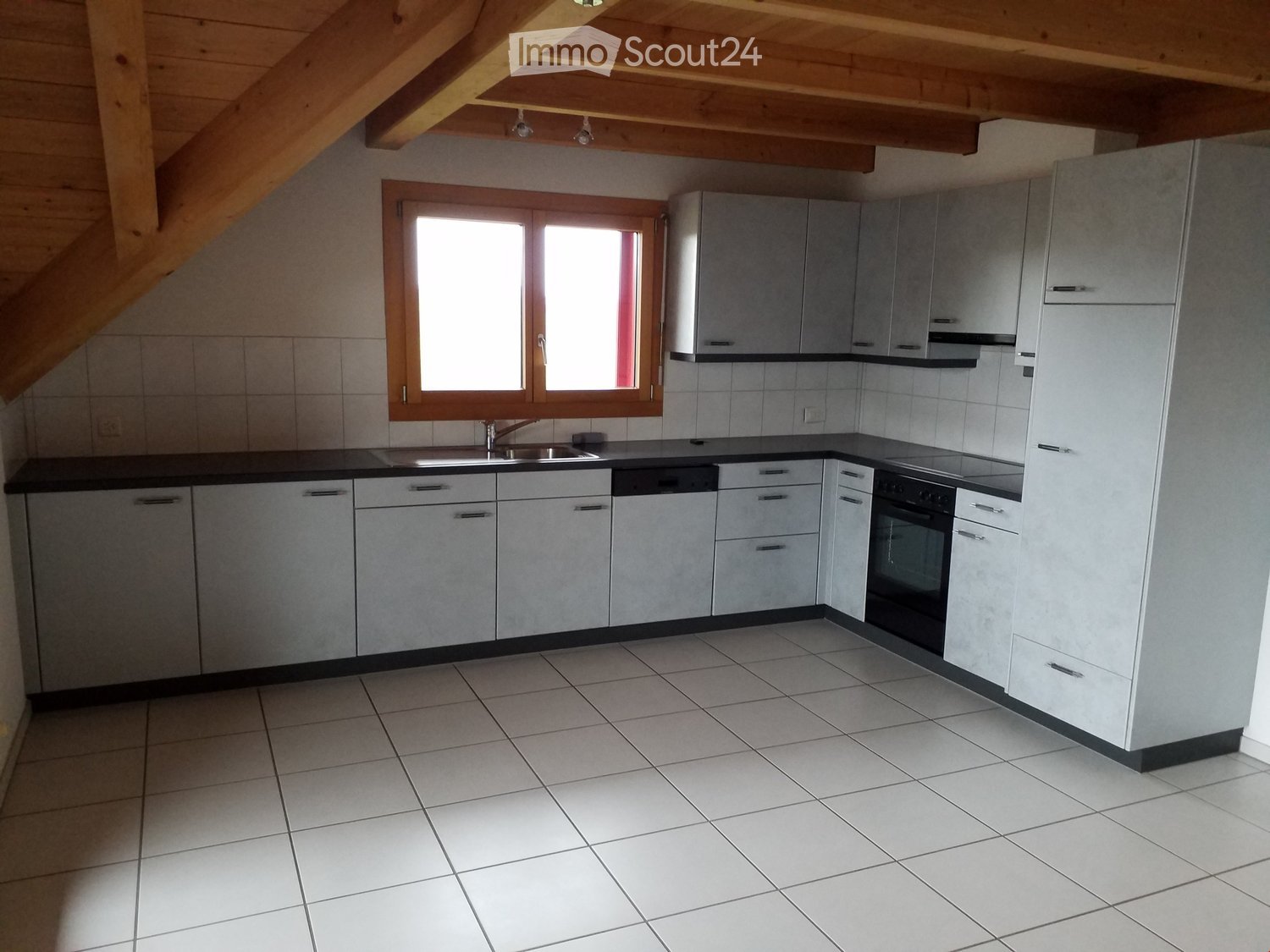 Modern kitchen with white tiled floor, grey cabinets, black countertops, and stainless steel appliances including a sink, oven, and dishwasher.